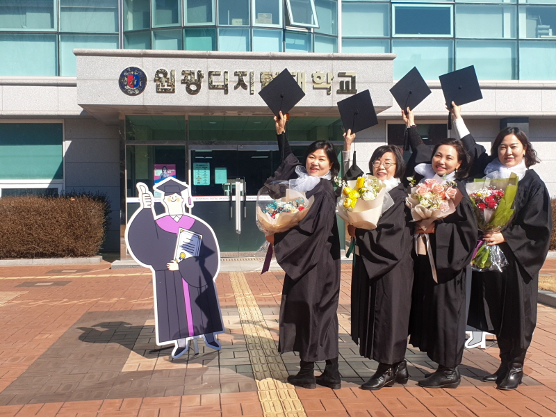 학사모를 들고 포즈를 취하는 졸업생들